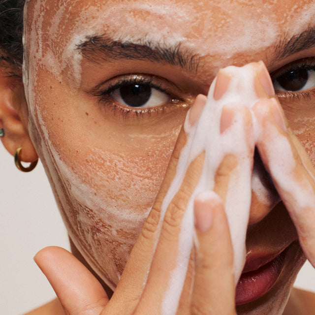 ILIA's the Cleanse foamed up on a models face with their hands applying it.